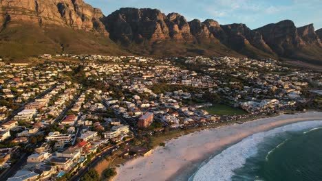 south african skyline of camps bay with 12 apostles in background at sunset, aerial