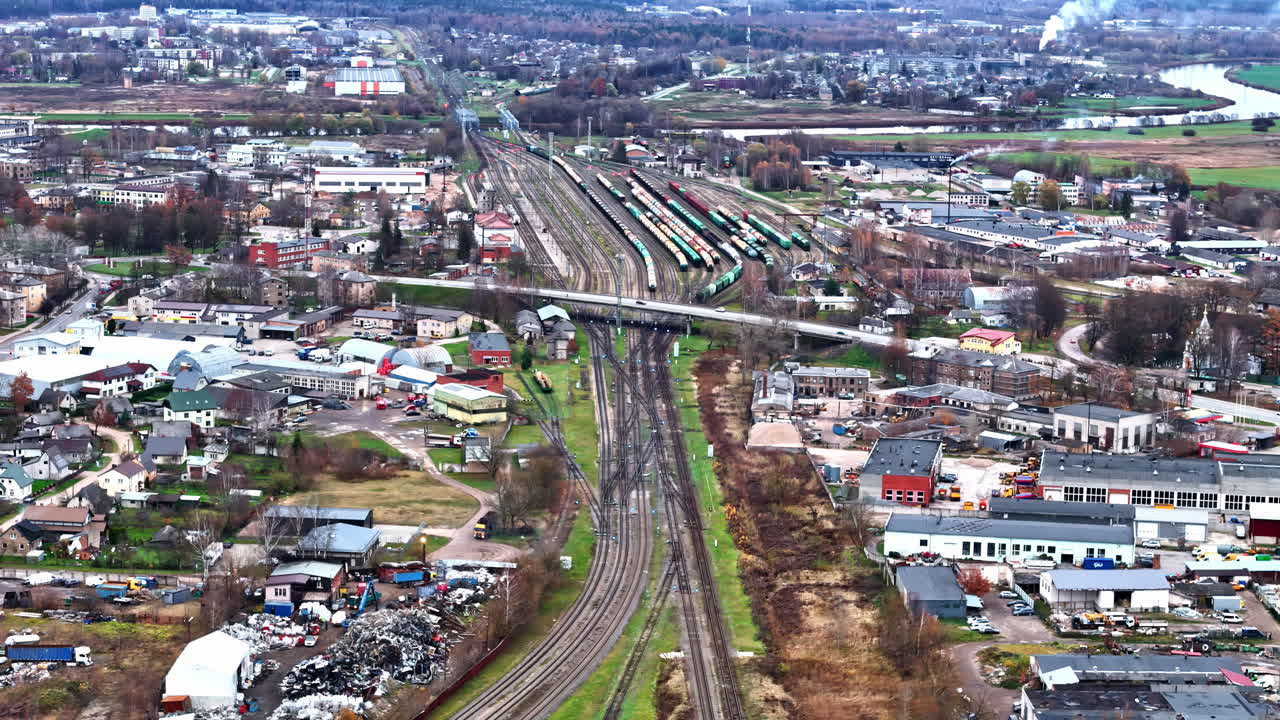 Carrellata aerea in avanti sopra un incrocio ferroviario e uno scalo merci che attraversa la città di Jelgava, Lettonia, in autunno.