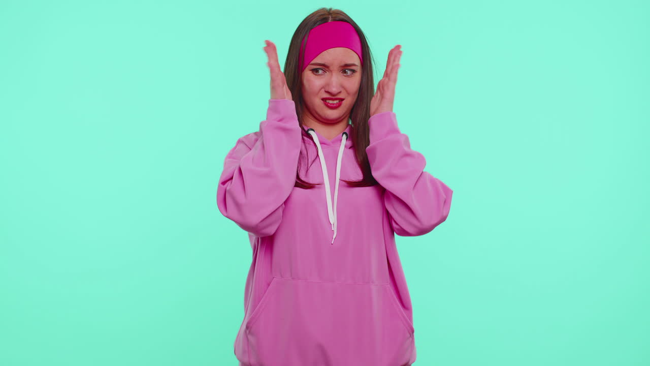 Student girl in pink hoodie closing eyes showing stop gesture, confused shy scared to watch