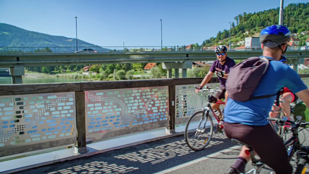 Cyclists on bridge greet each other while pedaling. Slovenia