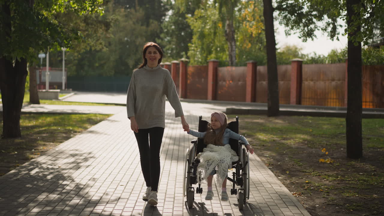 mujer feliz y niña unida de manos disfrutando de un paseo en el parque