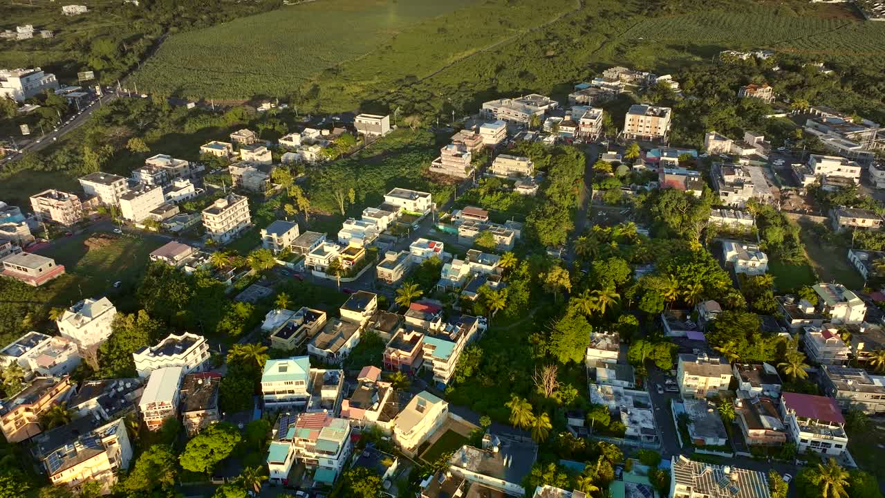 Grand Baie, Mauritius, Aerial sunset view over residential housing in lush green tropical environment, golden light over peaceful island neighborhood