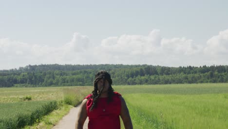 samson walking close pass screen from mid distance along old road in green pastures, biblical character with long dreads, israelite warrior and judge, black male in old testament, christian
