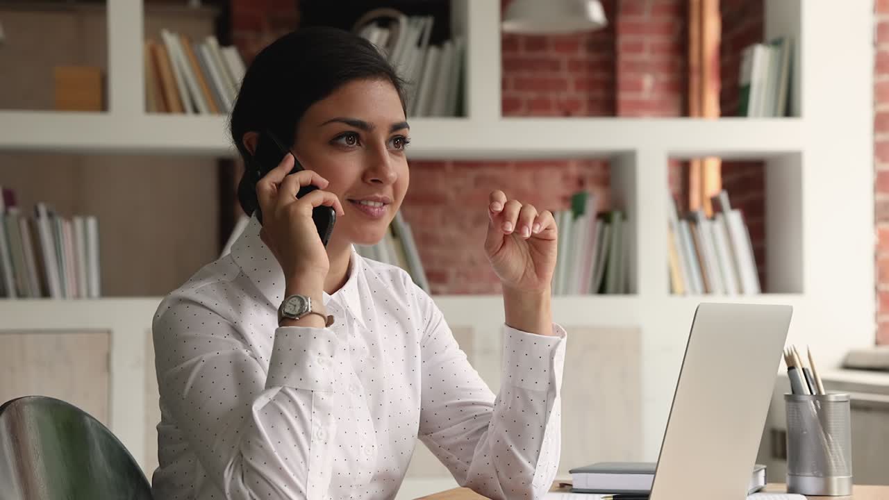 mujer de negocios india sentada en el escritorio hablando con el cliente por teléfono