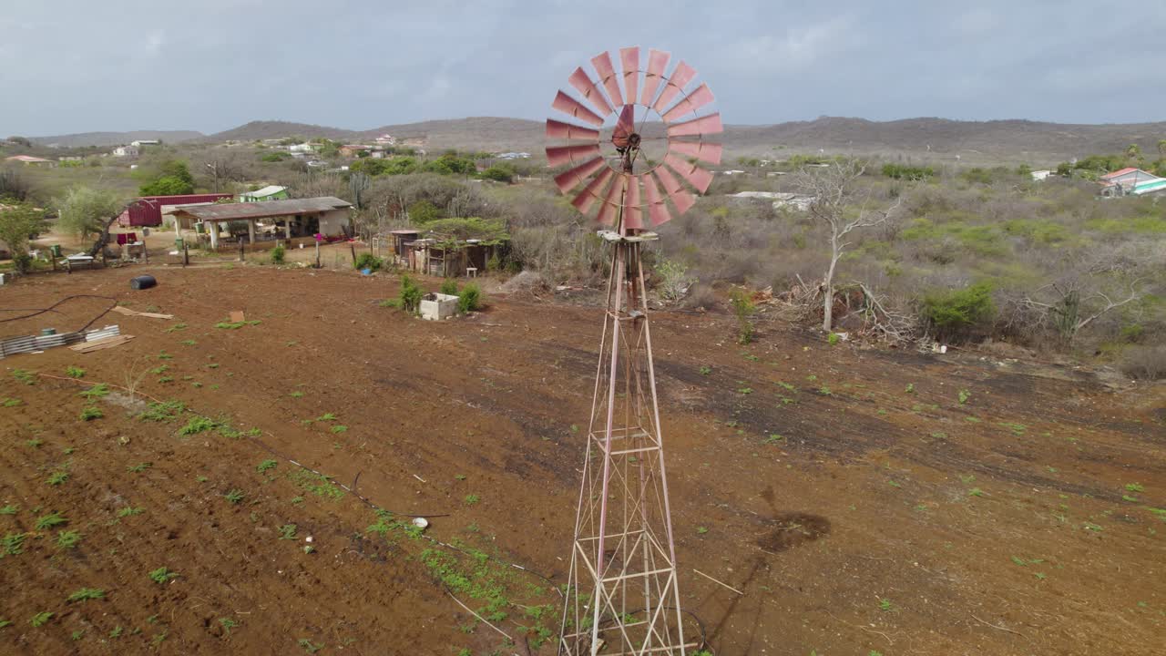 el molino de viento bombea agua en la remota granja ubicada en medio del desierto - órbita aérea cercana