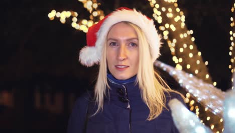 portrait of a woman smiling at the camera and playing in a santa hat