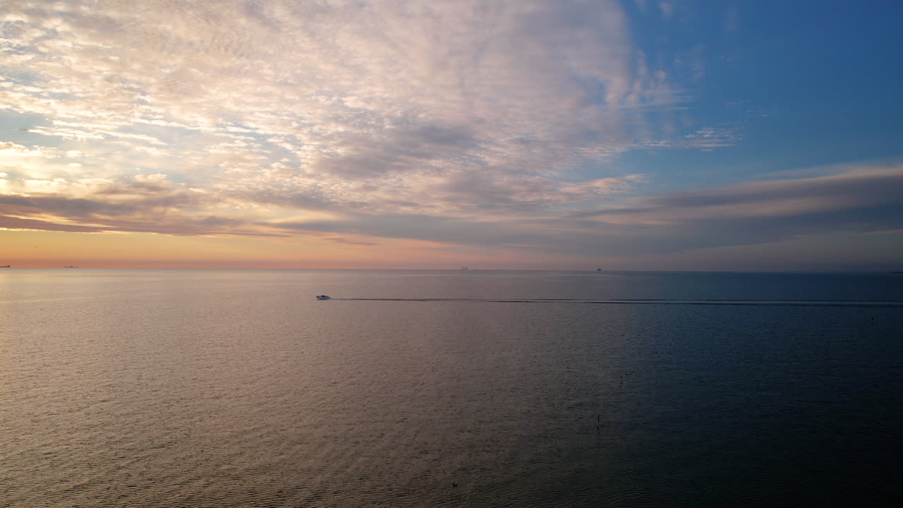 조용한 바다 표면 위에서 활기찬 일출의 높은 각도 항공기 보트 속도