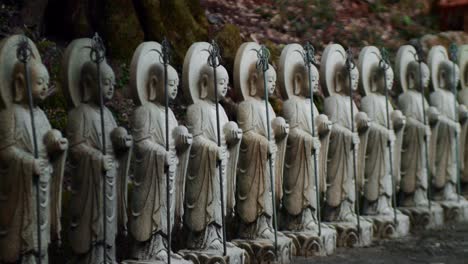 Slide-shot-of-small-stone-statues-outside-of-a-temple-in-Kyoto,-Japan-4K-slow-motion