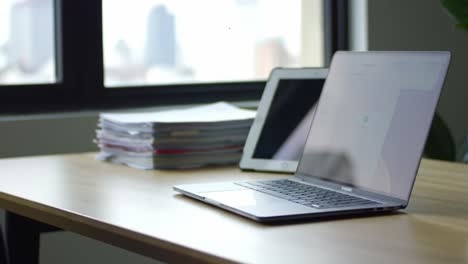 a modern workspace featuring a sleek laptop, a tablet, and organized paperwork, showcasing productivity and minimalist design in a contemporary office environment