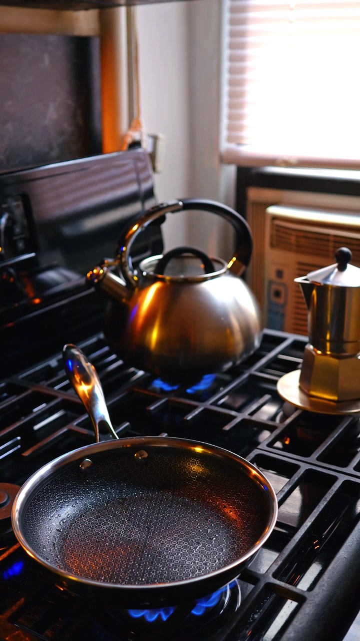 Empty non-stick pan heating on gas stove with blue flame. Vertical shot of empty metal pan sitting on burning gas stove in modern kitchen interior.
