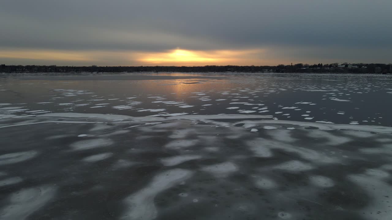 Frozen lake surface with different types of ice and snow on top during golden hour