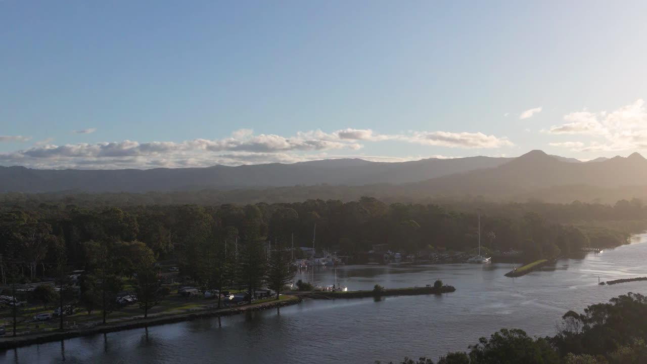 Aerial view of Brunswick Heads, NSW, showcasing a serene river and lush landscape under a setting sun