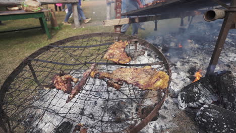 outdoor argentine asado with the last cuts of beef cooking over glowing embers - slow motion