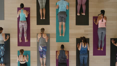 Vista-Superior-De-La-Clase-De-Yoga-De-Jóvenes-Sanos-Practicando-Pose-De-Cobra-Estirándose-Disfrutando-Del-Estilo-De-Vida-Físico-Haciendo-Ejercicio-En-El-Estudio