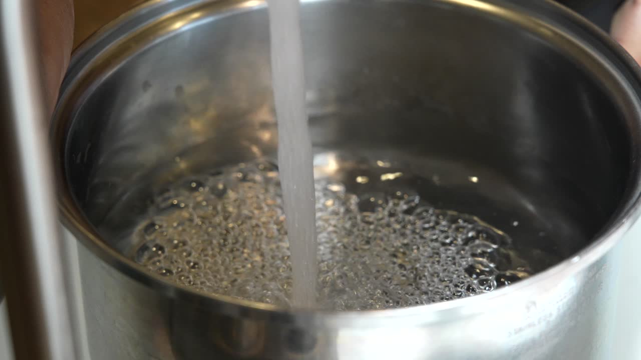 añadiendo agua a una olla para ponerla en la estufa