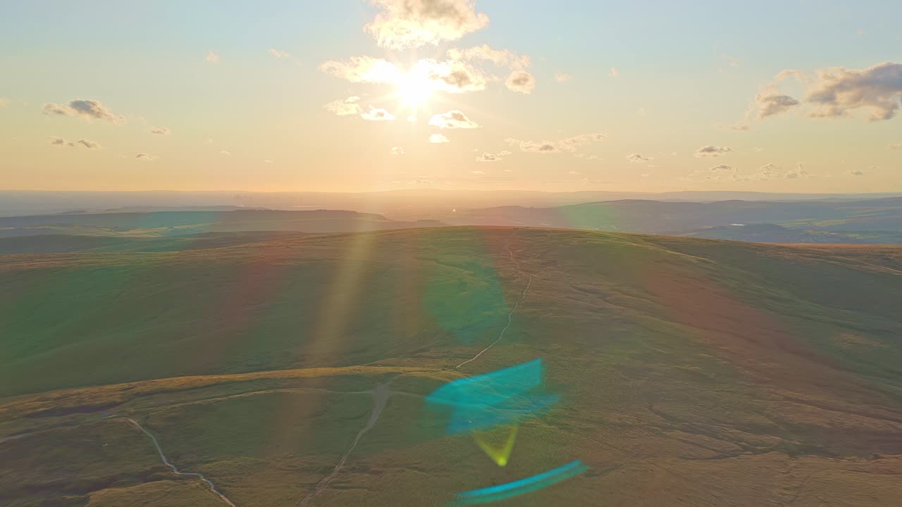 Flying toward the golden sun over rolling mountain hills, Peak District horizon, UK
