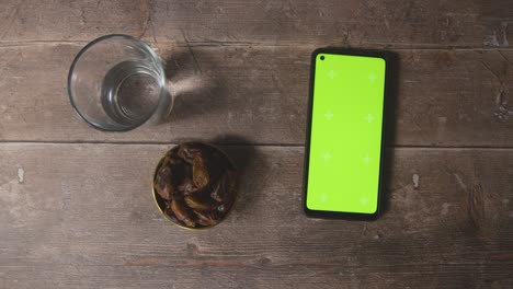 Handheld-Shot-of-Dates-and-Water-and-Green-Screen-Phone