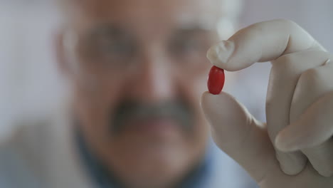 immunization treatment covid-19 coronavirus. a male scientist holds a red pill in his hands and looks at it close up slow motion. high quality 4k footage