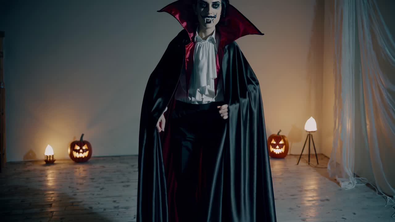 A low-angle video shot of a person in a vampire costume, showcasing a dramatic cape spread