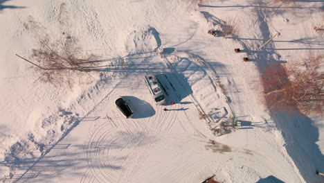 vehicles parked on snowscape surrounded by trees during sunny winter day