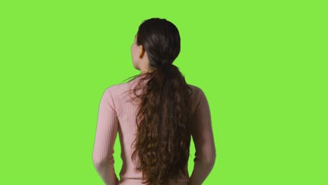 Rear-View-Studio-Shot-Of-Woman-Looking-All-Around-Frame-Against-Green-Screen-In-VR-Environment