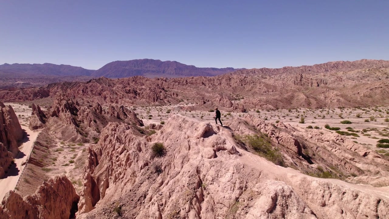 Um homem explorando formações rochosas deslumbrantes e vastas paisagens em uma região desértica remota em plena luz do dia.
