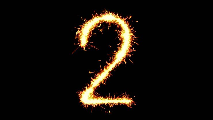 Numero 2 scritto con scintille luminose, particelle glitterate e fuochi d'artificio su sfondo nero in loop 4K.