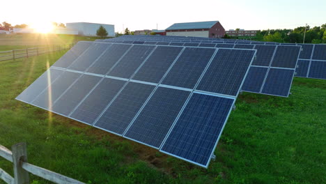 low aerial flyover of solar panel farm in america. sunset in background. sprawling renewable energy provider