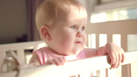 beautiful baby standing in crib. toddler learning to stand in bed at home