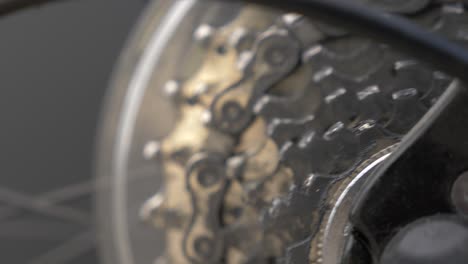 slow motion zoom into moving bicycle wheel and gear chain cogs, low depth of field