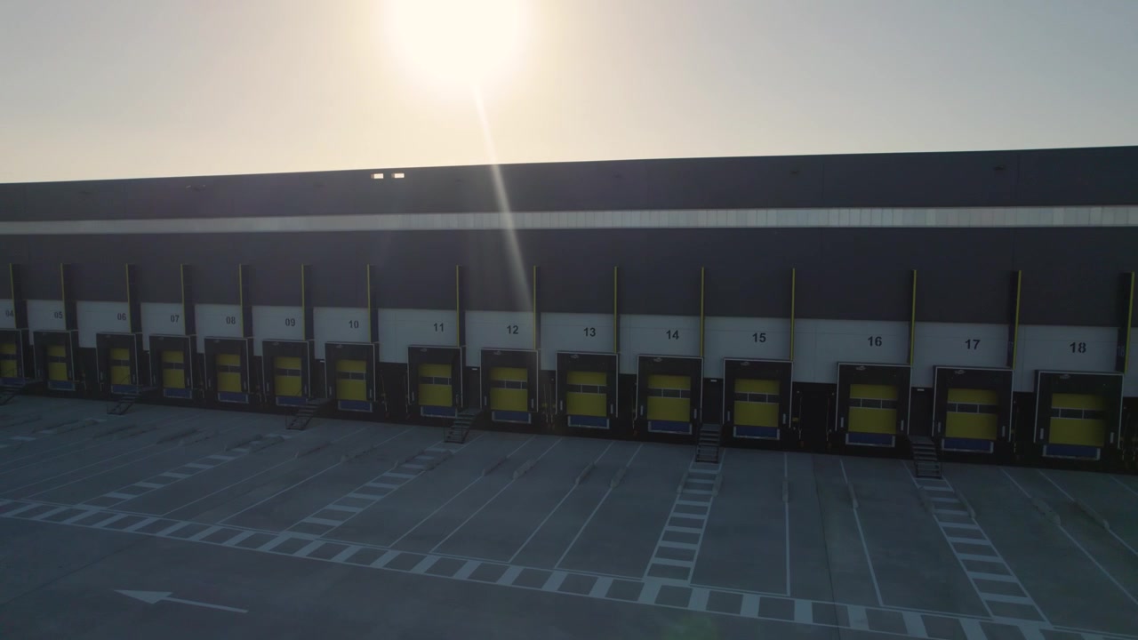 empty loading dock of a warehouse, with several numbered large yellow doors at sunset