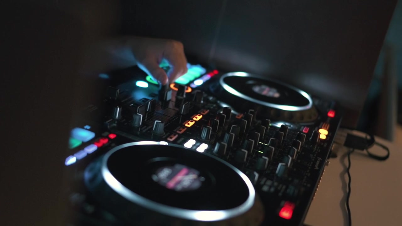 Un DJ mixa abilmente tracce su giradischi digitali, creando suoni dinamici in un ambiente poco illuminato