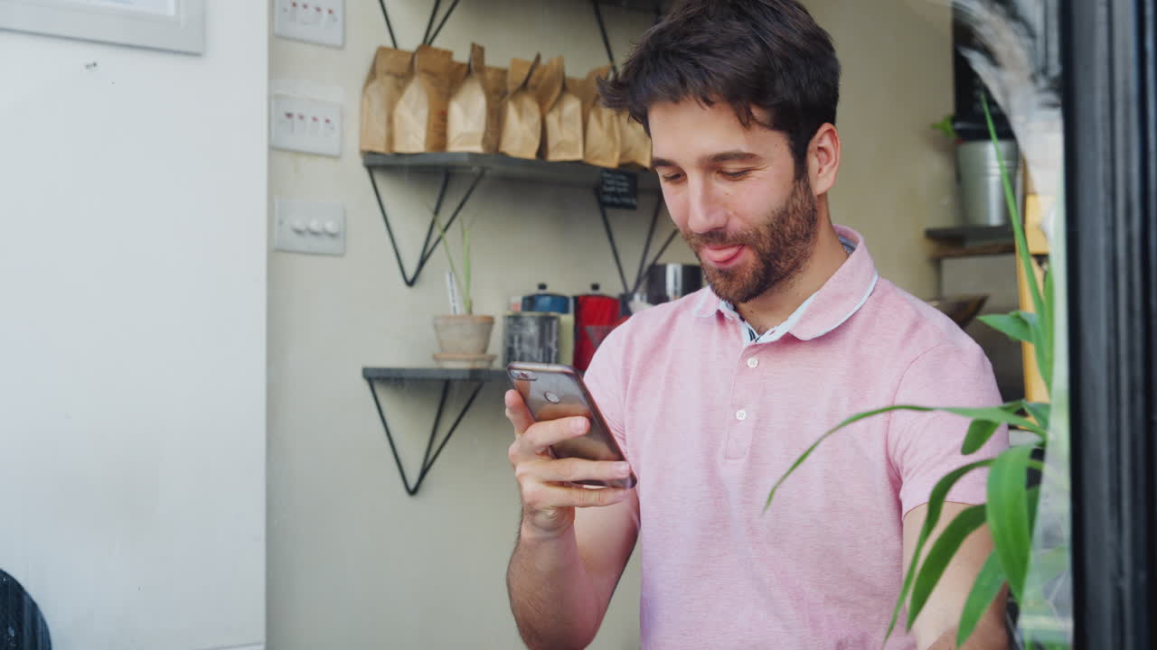 joven en la cafetería mirando el teléfono móvil