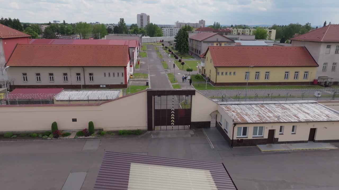 Drone tracking shot following outer prison wall lined with barbed wire and guard towers