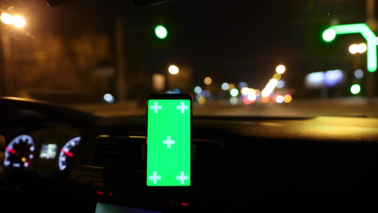 teléfono inteligente con pantalla verde en el fondo de conducción de coche de la noche