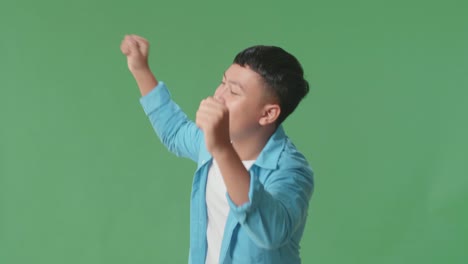 side view of smiling asian man dancing in a green screen studio