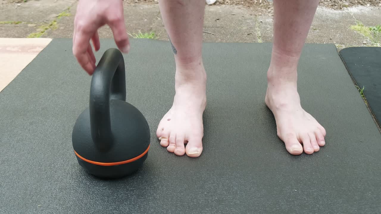 Front shot close up of a man lifting a 16 kg kettlebell outside in slow motion 4K