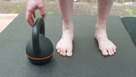 front shot close up of a man lifting a 16 kg kettlebell outside in slow motion 4k