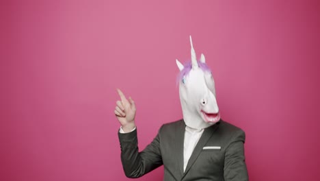 happy guy in gray suits he is having fun with unicorn mask. fool's day