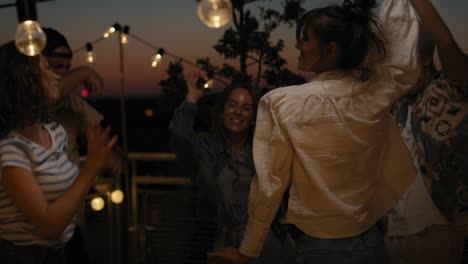 Group-of-friends-dancing-at-the-party-in-top-of-the-roof-at-night.