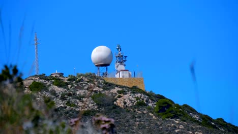 un radar meteorológico con una gran esfera blanca en la cima de una montaña
