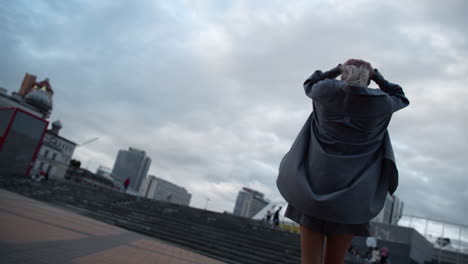 woman walking big city wearing casual clothes in rainy weather downtown dusk.