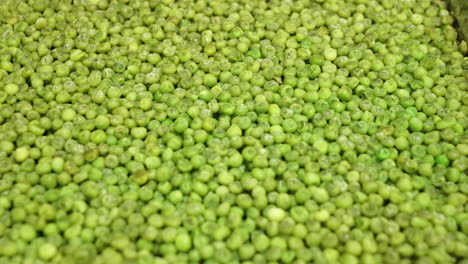 closeup of green peas cooked in a metal tray of an industrial kitchen