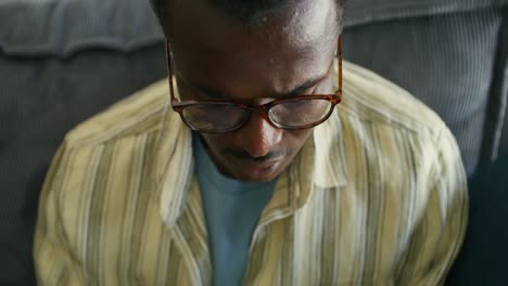 man wearing glasses sitting on a couch