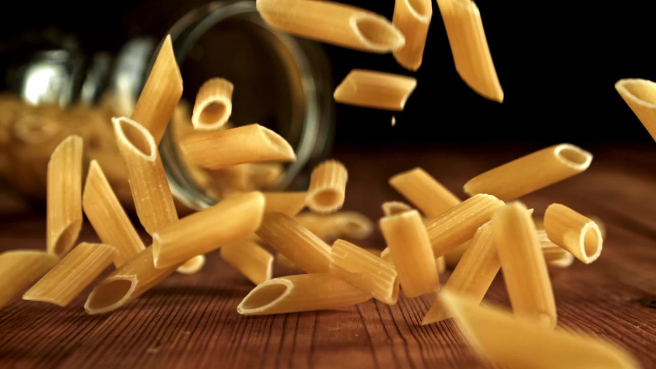 Penne che cadono al rallentatore su un tavolo di legno