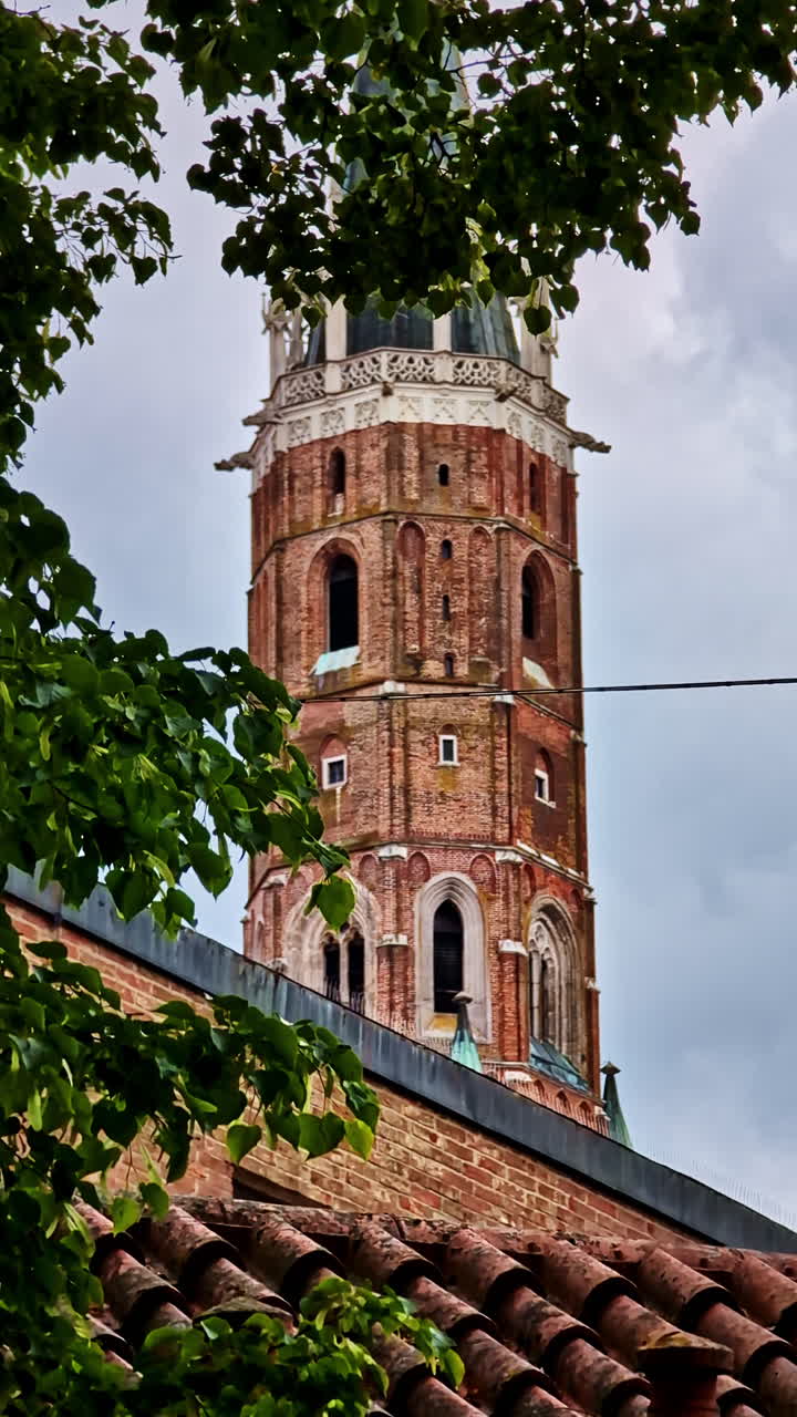 Close-up of gothic brick tower of St. Martin’s Church seen through trees, Landshut, Germany
