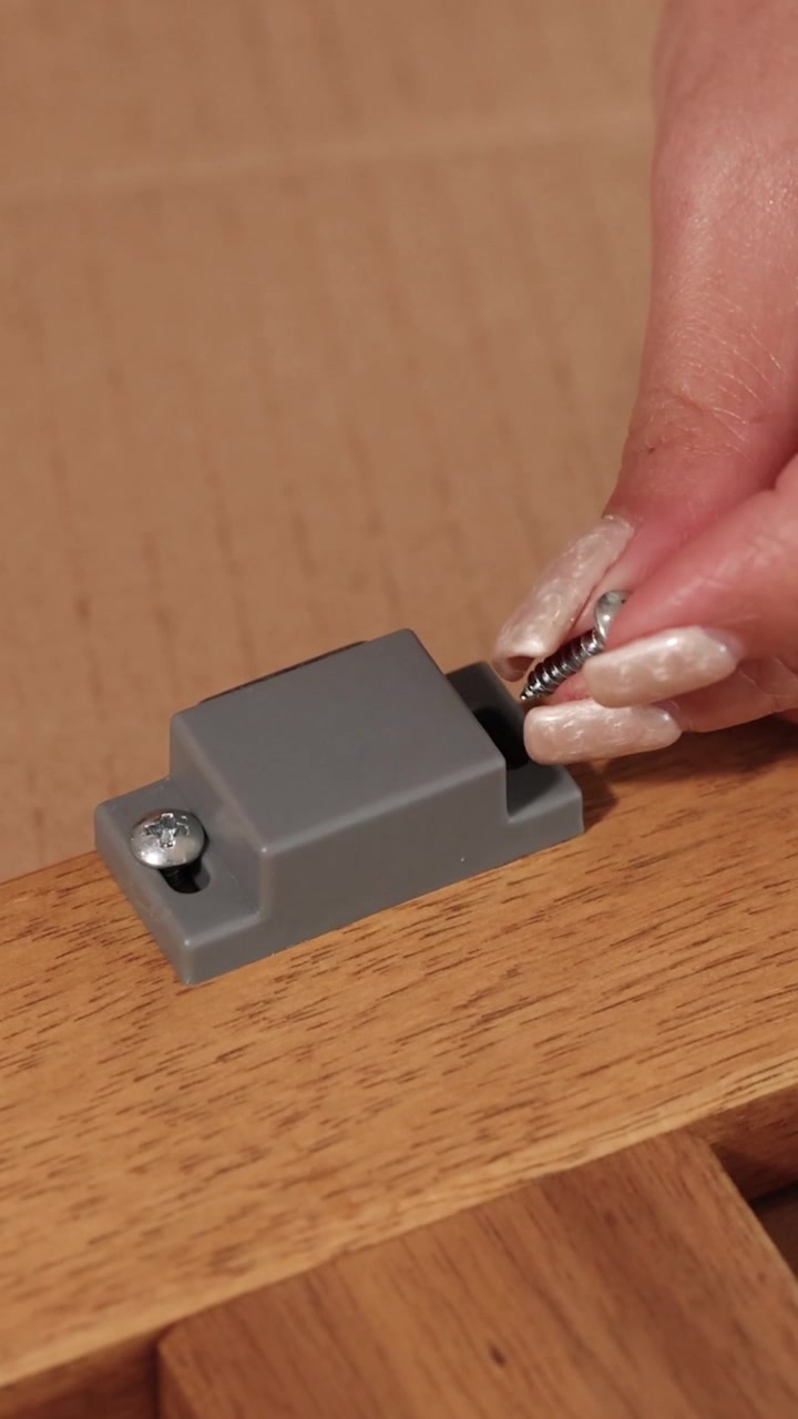 Primi piani che mostrano mani che posizionano una chiusura magnetica e inseriscono viti in mobili di legno.