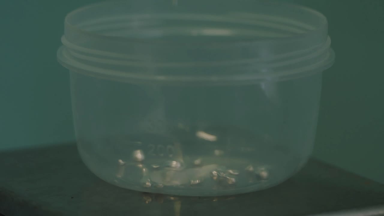 verter líquido en un recipiente con piezas metálicas