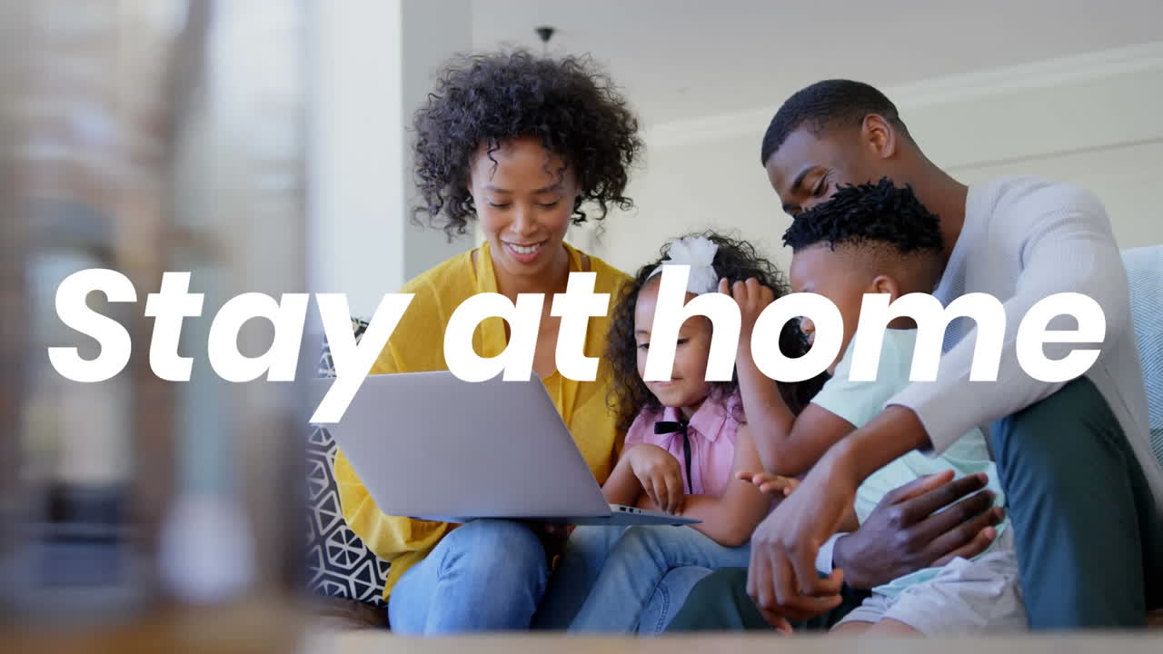 Animation of stay at home text over parents with son and daughter using laptop at home