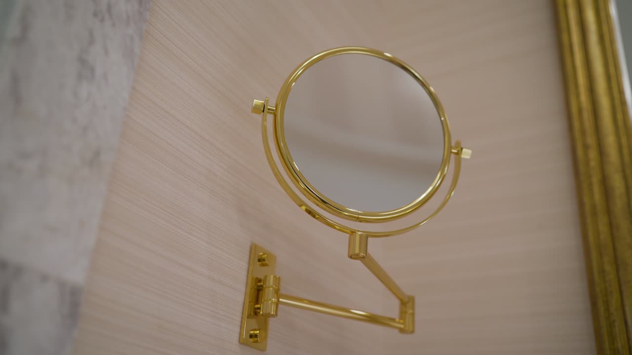 Nuovo bagno con carta da parati a fantasia, pavimento scintillante, specchio rotondo con cornice dorata decorativa e lavabo nero. Uno specchio rotondo dorato nel bagno.